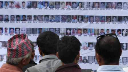 People looking at photos of missing persons displayed on a wall