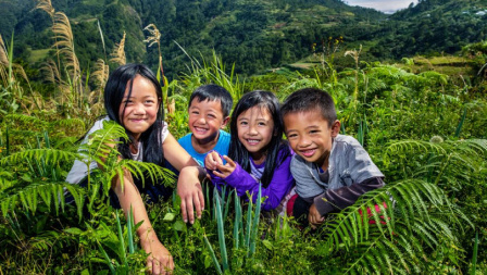 Children smiling in the middle of plants in mountain