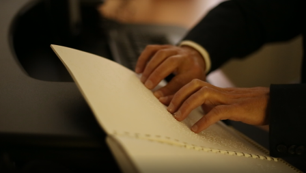 closeup of a pair of hands reading a braille document