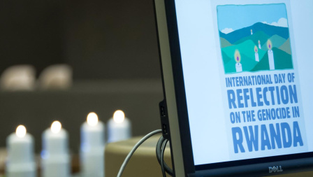 A laptop shows the words "International Day of Reflection on the Genocide in Rwanda". Candles are seen in the background. 