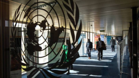 People walking in a corridor with WHO emblem in the foreground