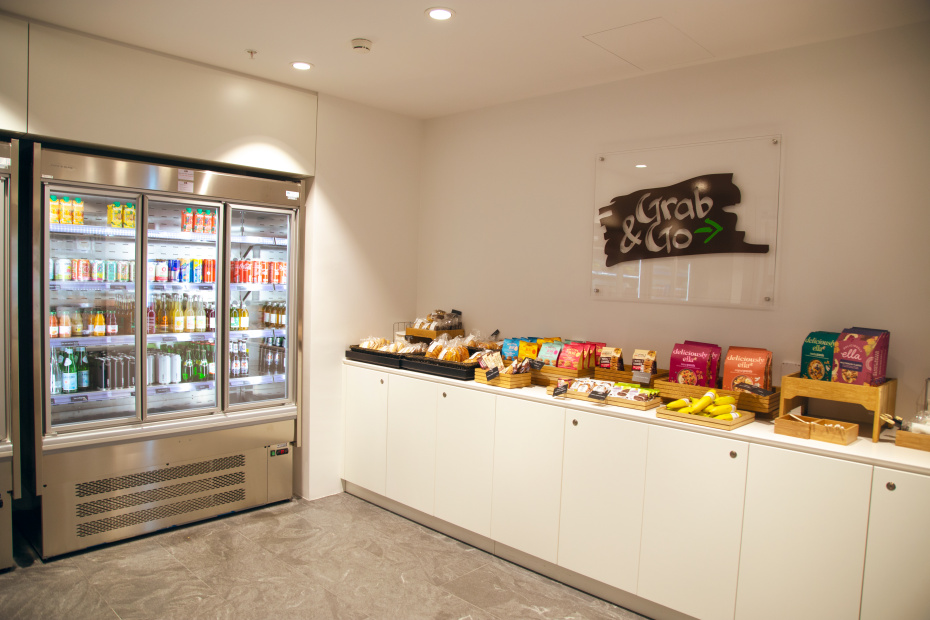 A refrigerator filled with cold drinks, next to a table full of snacks. Above the table is a sign that reads "Grab N Go".