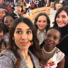 Several female participants in the Young Activists Summit take a group selfie inside the Human Rights Council room