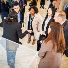 A tour guide, seen from the back, giving explanations to a group of visitors who are leaning forward, attentively following the guide's words.