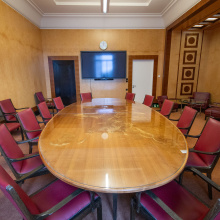 The setup in Conference Room II, a large table with chairs around, and a TV at the back wall.