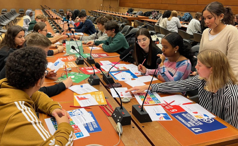 A group of students participating in a hands-on workshop in one of the UN conference rooms. In front of them are different materials with the SDG branding.
