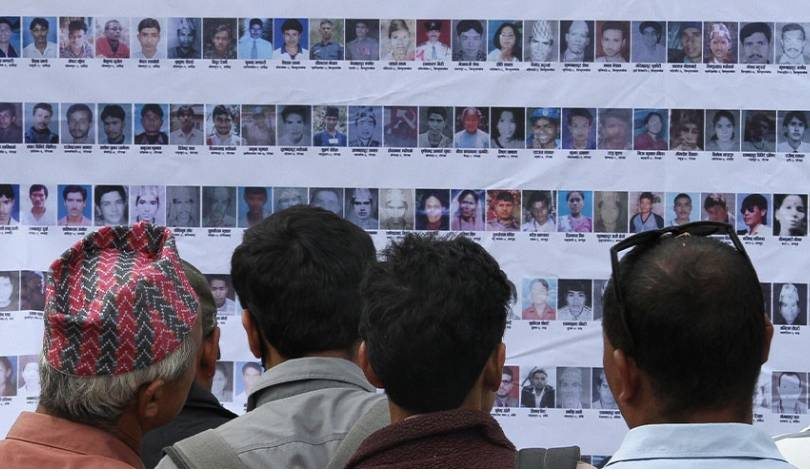 People looking at photos of missing persons displayed on a wall