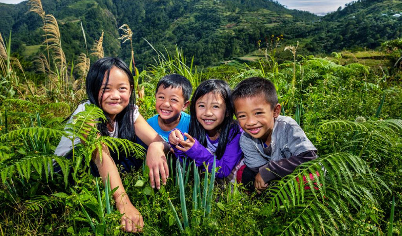 Children smiling in the middle of plants in mountain