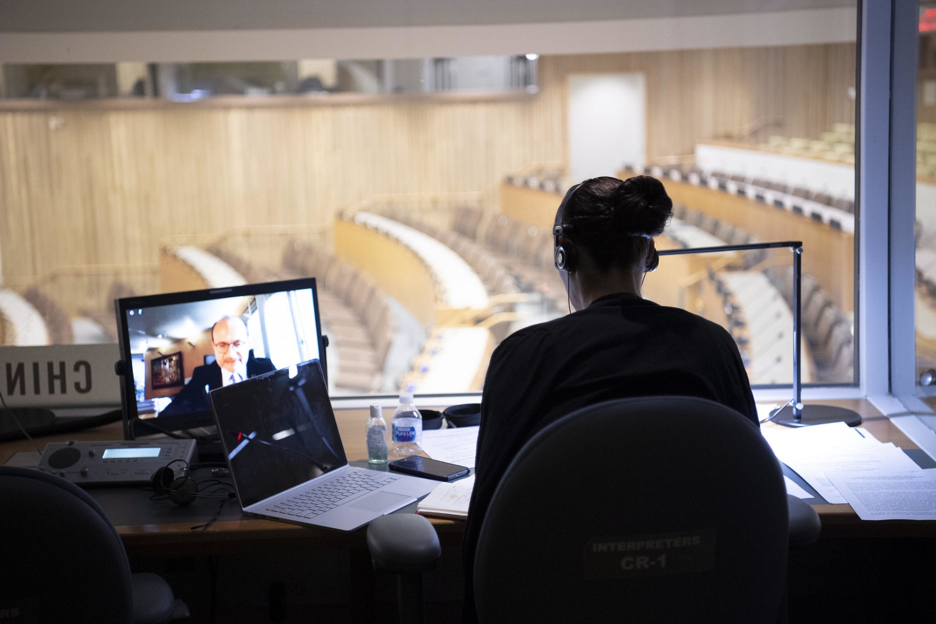 an interpreter sits in a booth in a UN conference room.