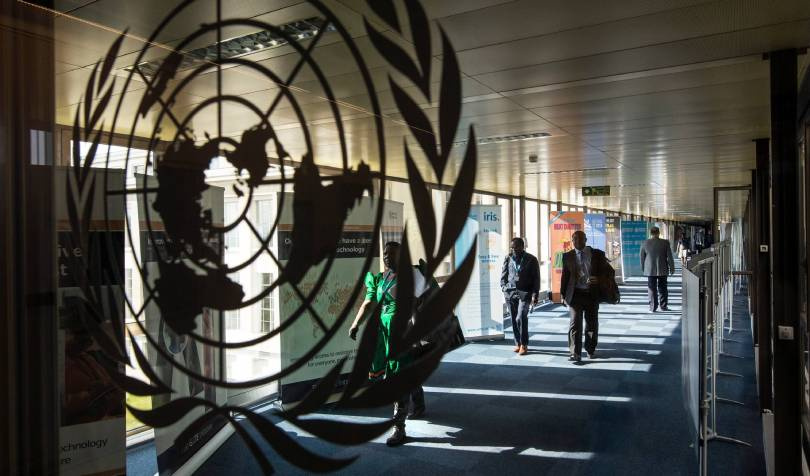 People walking in a corridor with WHO emblem in the foreground