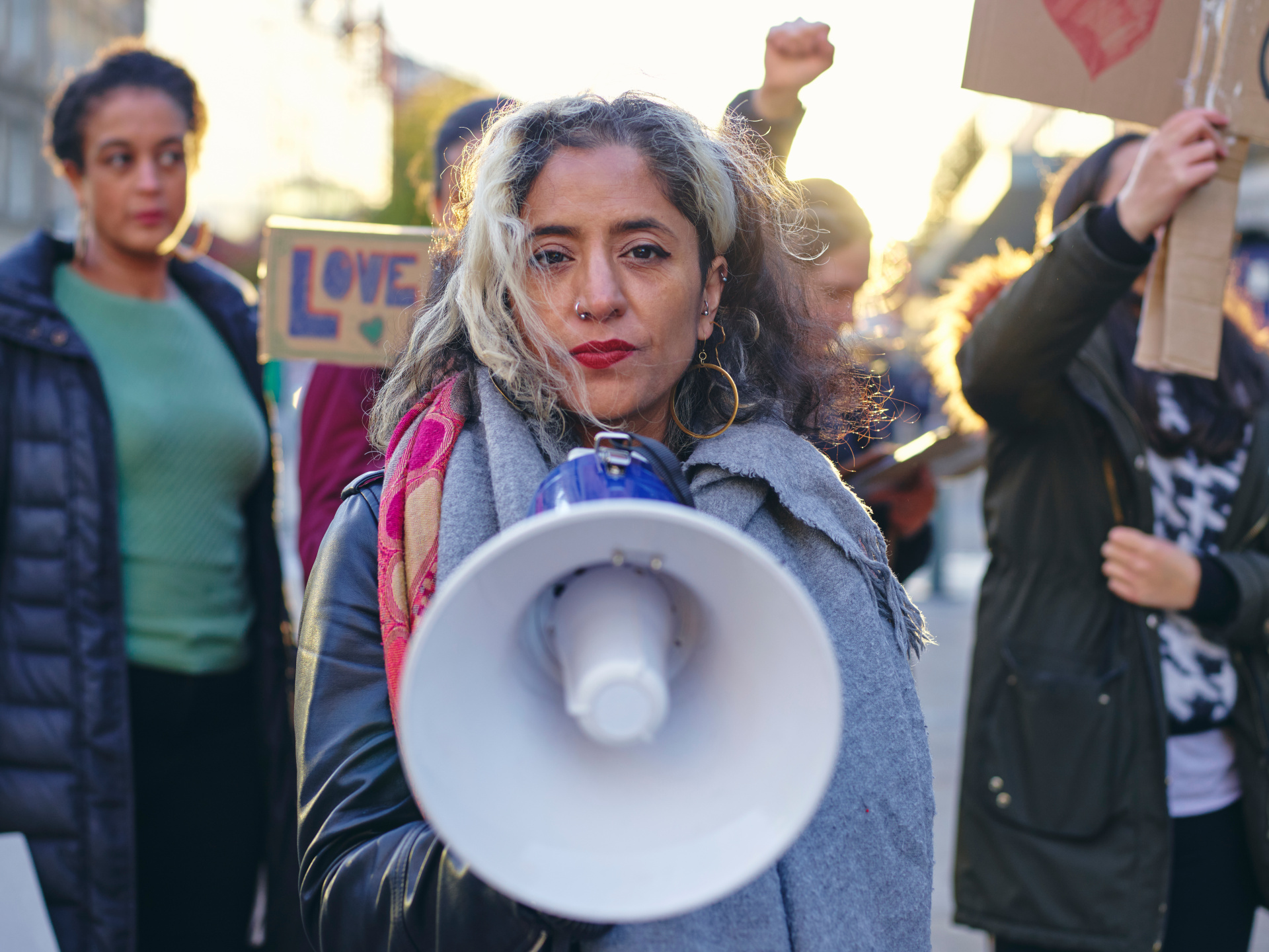 A young woman, accompanied by several other youth, speaking through a megaphone during a demonstration
