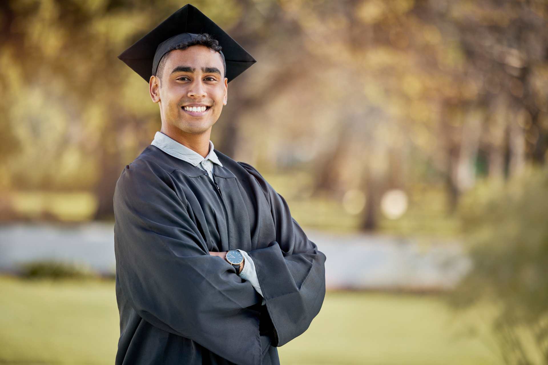 A recent graduate in graduation gown smiling at the camera