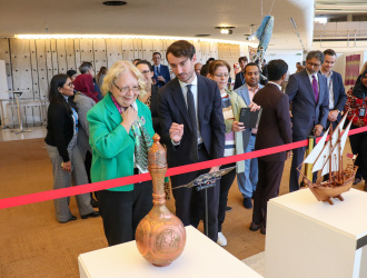 The UNOG Director-General looking at an exhibition. A vase and a model ship are seen as exhibition items. 