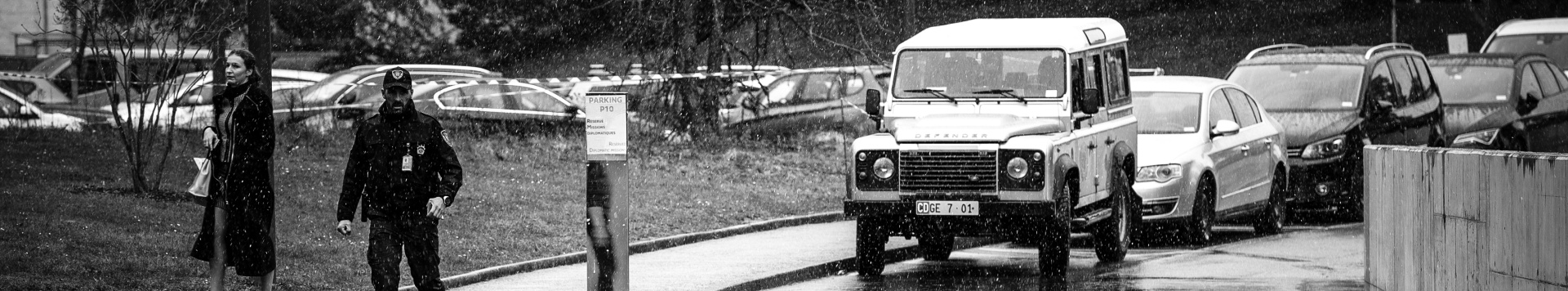 A car driving on the streets within the Palais des Nations compound. the image is in black and white.
