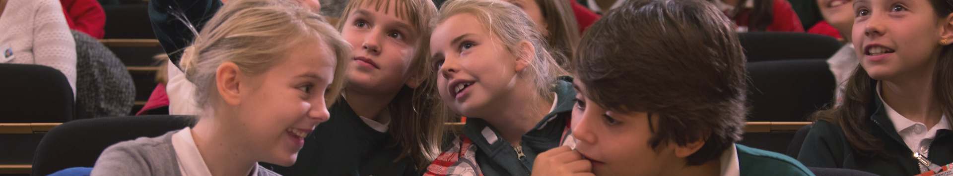 A group of children sits in one of the UN meeting rooms, following the programme.