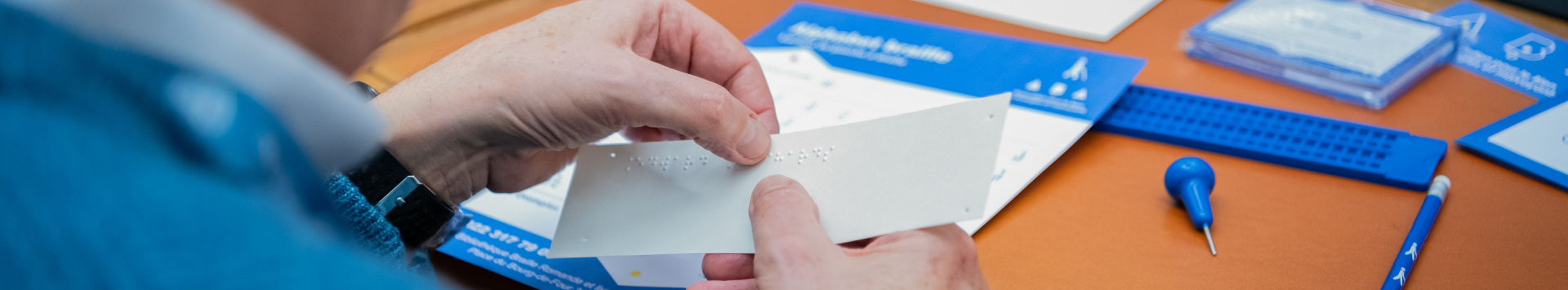 Close-up of hands holding a piece of paper with Braille embossing on it. 