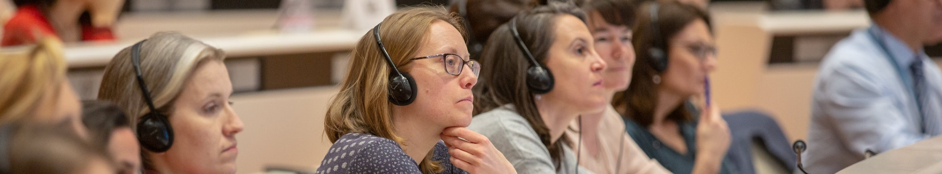 Meeting participants sitting in one of the conference rooms, listening attentively through the earphones. 