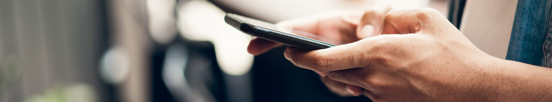 Closeup on hands typing into a mobile phone.