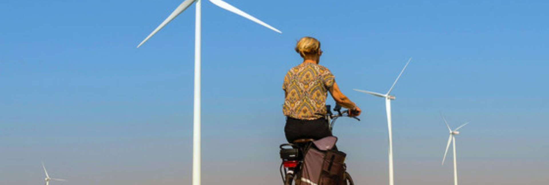 A cyclist on a road paved with wind turbines